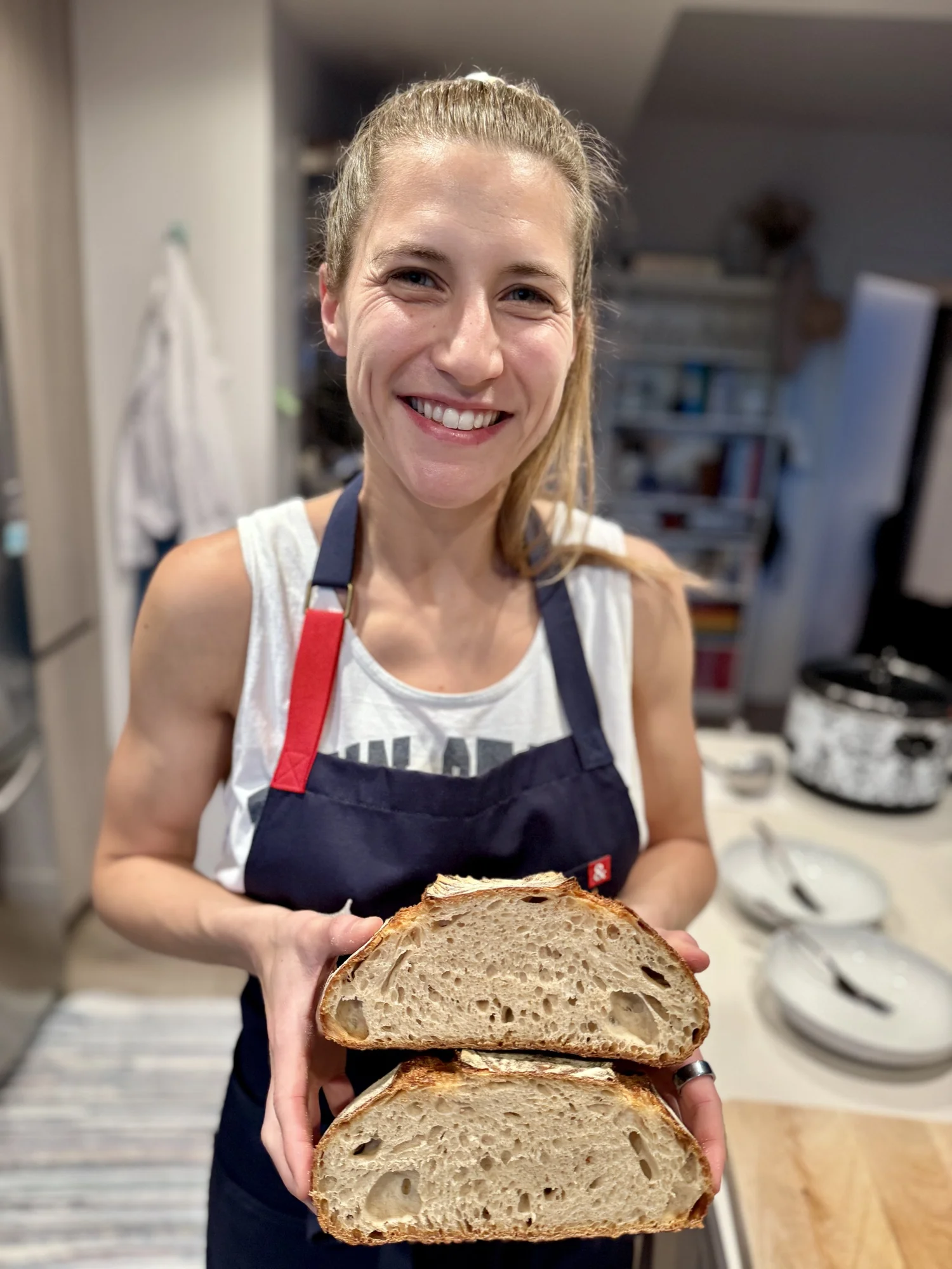 Kelsey Tenney in her kitchen holding a freshly baked, sliced sourdough loaf